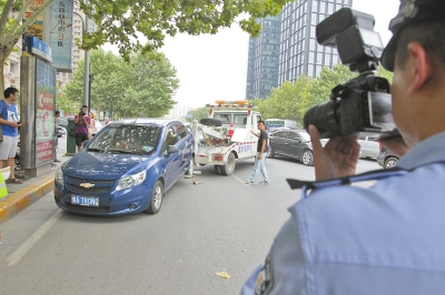 在金水路，交警對(duì)在機(jī)動(dòng)車道違法停放的車輛施行拖離