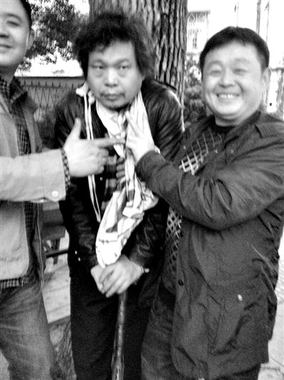 兩名接訪人員與患有癌癥的訪民段新德合影時(shí)，面帶笑容擺出勝利的手勢(shì)。