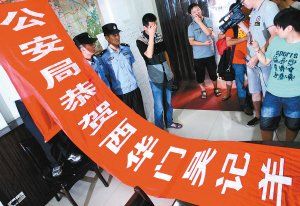 面對警方收繳的條幅，老板楊某也不好意思地用手遮擋臉