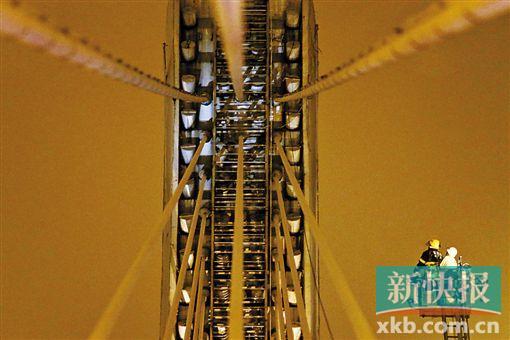 截至今日零時(shí)，男子仍未有下橋舉動(dòng)。圖為公安和消防人員乘消防云梯在高空上和男子交談。