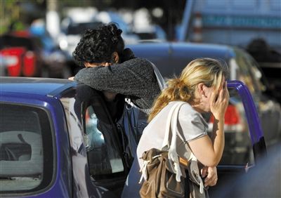 27日，遇難者親友在火災(zāi)現(xiàn)場旁哭泣。