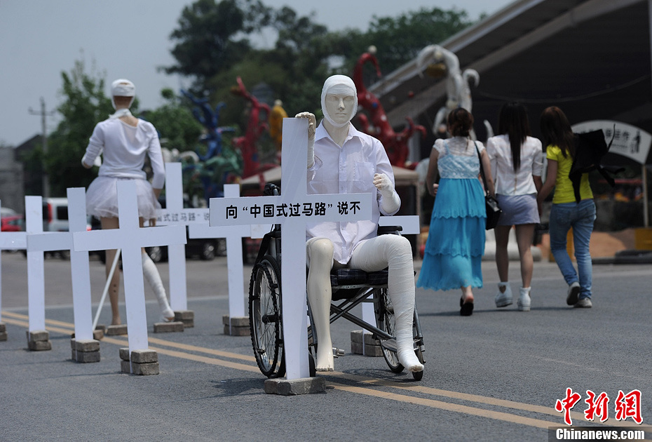 4月16日，重慶市洋人街上擺放著兩個(gè)受了傷的塑料人像“模特”，旁邊十字架上寫著向“中國式過馬路”說不