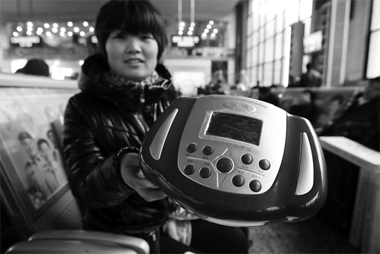 火車(chē)站候車(chē)室，李女士向記者展示她準(zhǔn)備孝敬父母的按摩儀