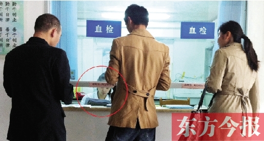 昨日，鄭州市二七區(qū)疾控中心辦證大廳，血檢窗口內(nèi)一名女工作人員，邊接受辦證者咨詢邊看報(bào)紙