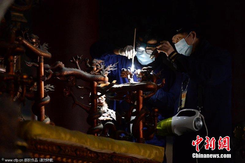 圖為工作人員使用軟毛刷和吸塵器對太和殿的金漆雕龍寶座除塵。