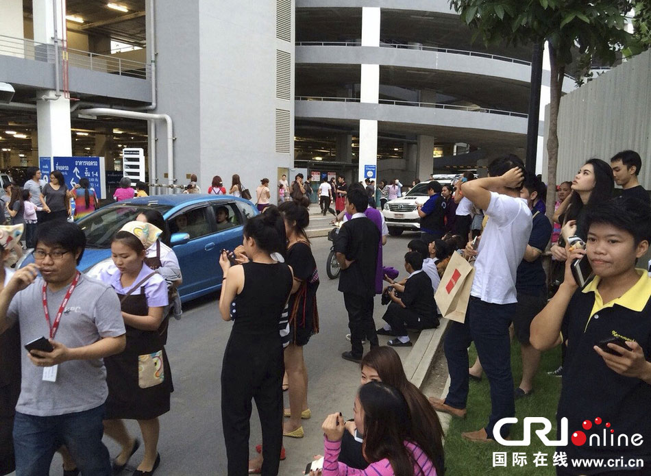 當?shù)貢r間2014年5月5日，泰國清萊，工人們站在一棟大樓外避難。