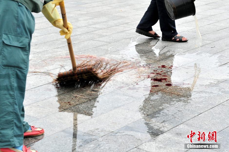 圖為環(huán)衛(wèi)工人在清理案發(fā)地點(diǎn)的血跡。