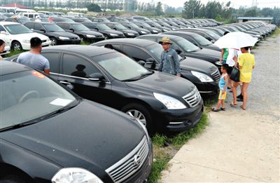 昨日，市民在山東棗莊一家拍賣公司場地上查看待拍賣公車。當(dāng)日，棗莊市103輛公車公開拍賣。新華社記者