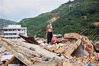 8月9日,龍頭山鎮(zhèn),一位老者在自家房屋廢墟上尋找家當。