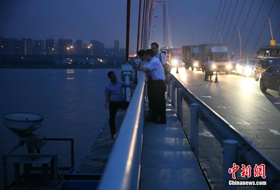 圖為武漢警方談判專家正在與翻爬至大橋外側(cè)護(hù)欄的劫持者談判。