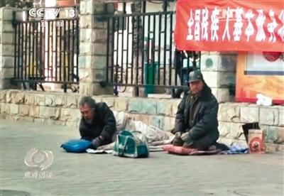 工人體育場(chǎng)北路，兩位乞討者路邊乞討，并輪流扮成“病人”（躺地者）。 央視截圖